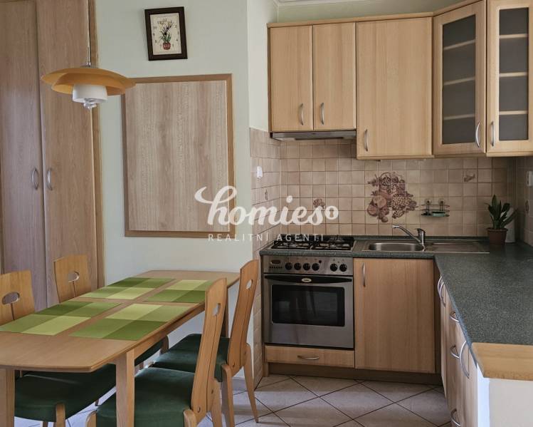 A kitchen in a 3-room apartment with a wooden decor and a dining table with four chairs.