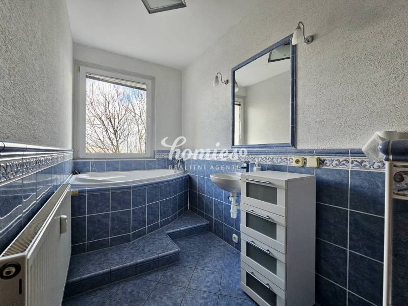 A bathroom with blue tiles and a large bathtub in a 3-room apartment.