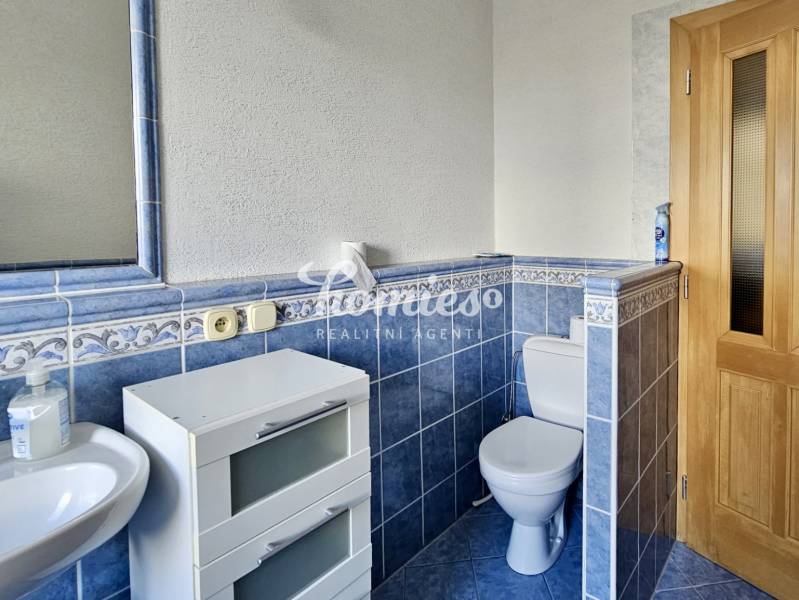 A bathroom with gray-blue tiles, a sink, and white storage furniture in a 3-room apartment.