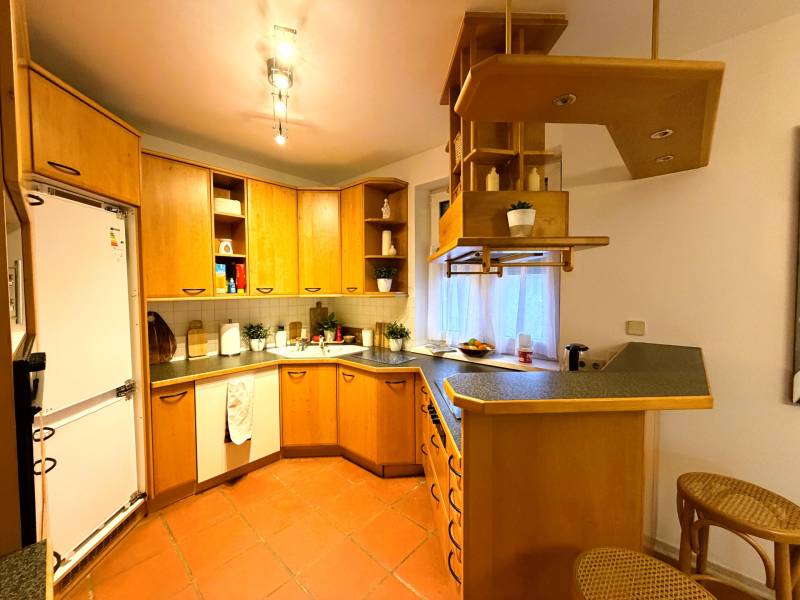 A kitchen in a 3-room apartment with wooden cabinets and a bar counter.