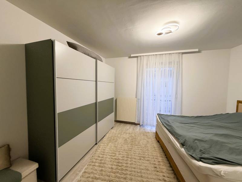 Bedroom in a 3-room apartment with a wardrobe, bed, and floor with wooden decor.