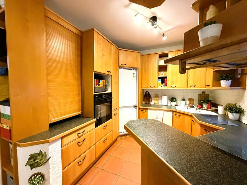 A kitchen in a 3-room apartment with a corner unit and a floor with a wood decor.