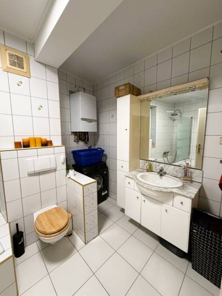 Bathroom in a 3-room apartment with white tiles, a washing machine, and a sink.