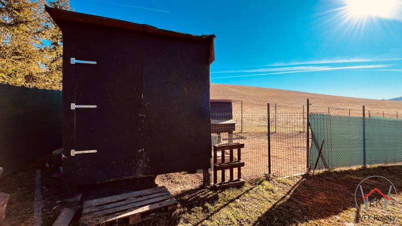 A wooden shelter and fencing on a field in the Construction of houses in Prosačov.