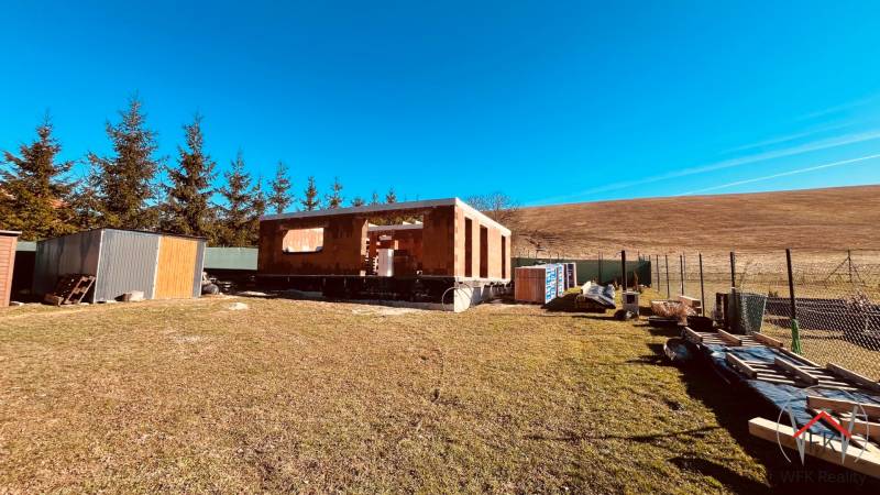 Construction of houses in Prosačov on Prosačová Street surrounded by nature and a clear sky.