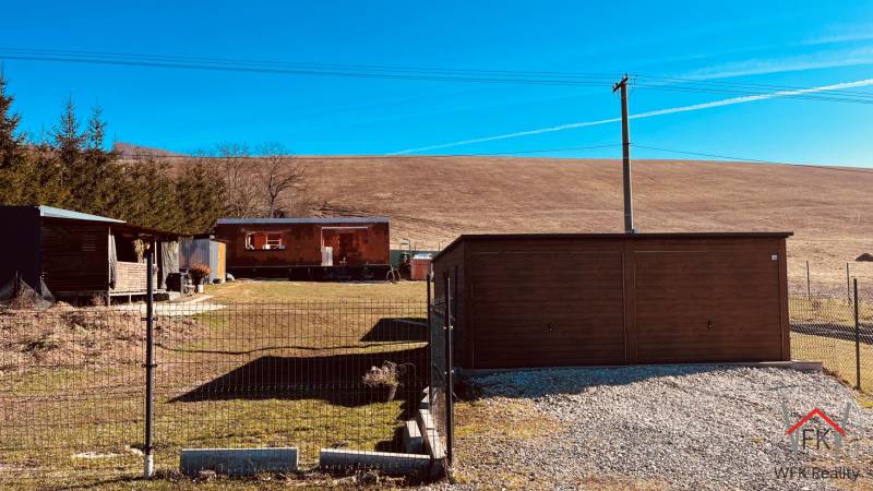 Construction containers on Prosačov Street in Prosačov surrounded by small trees and a fence.