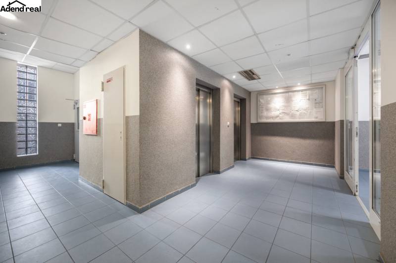 Lobby with elevators, blue floor, illuminated ceilings.