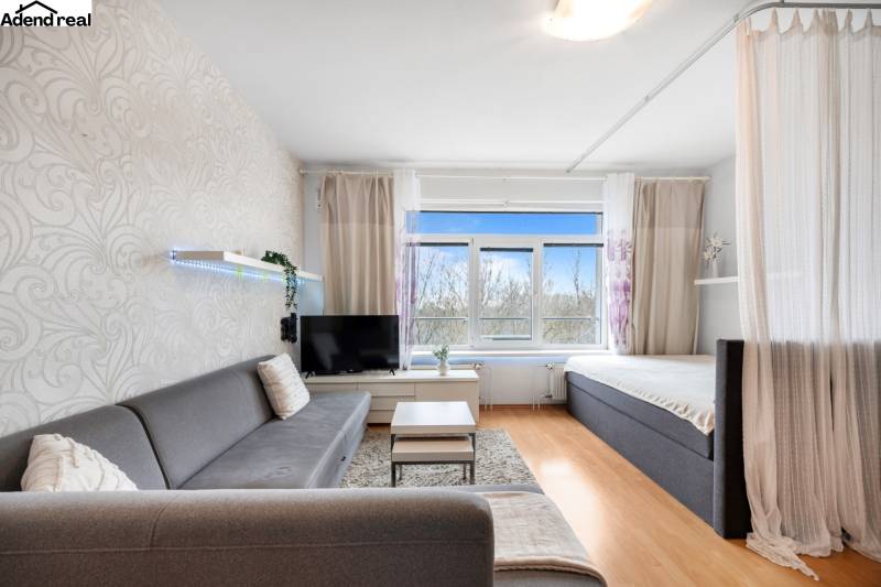 Living room with a sofa, curtain, and television, floor with wooden decor.