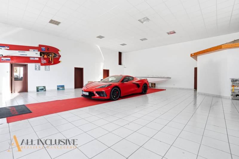 The commercial premises display a car and a boat with a white floor and sports equipment.