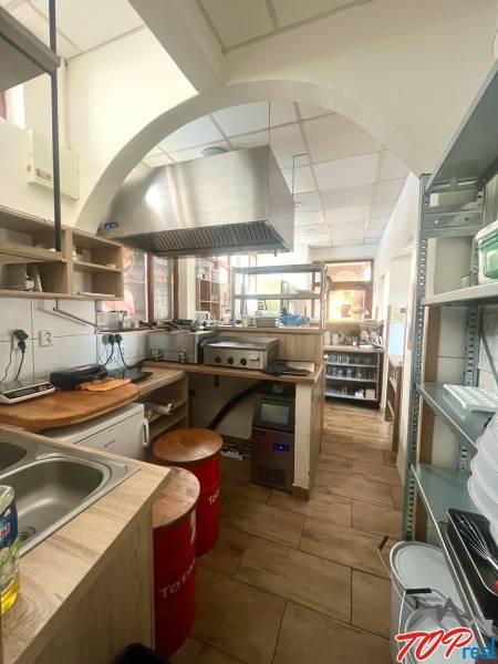 Gastro premises with wooden decor, kitchen unit, extractor hood, appliances, shelves, chairs.