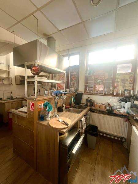 A kitchen in a gastro space with a wooden decor floor, equipped with modern appliances.