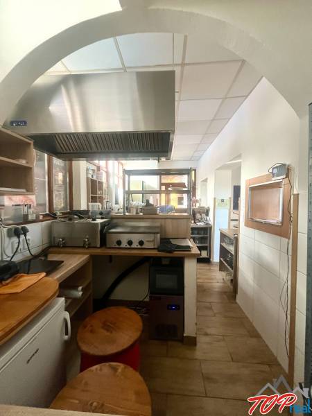 A kitchen space with a stainless steel range hood and a wooden decor floor in a gastro area.