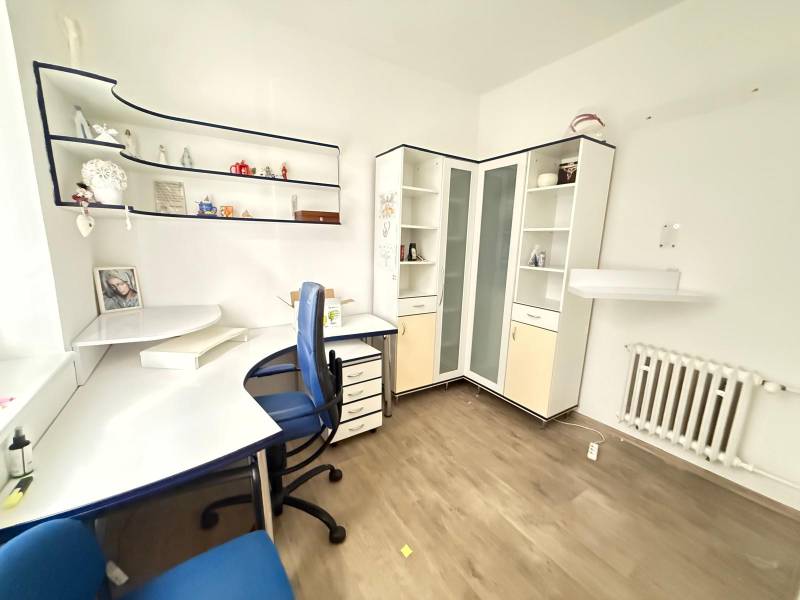 Office with a desk, shelves, and a wooden decor floor.