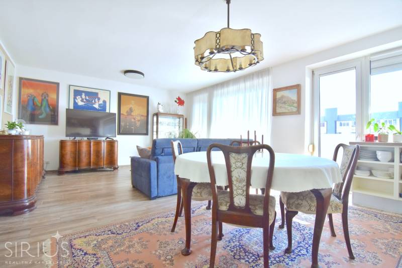 Living room with a dining table, sofa, and wood-patterned flooring in a 3-room apartment.