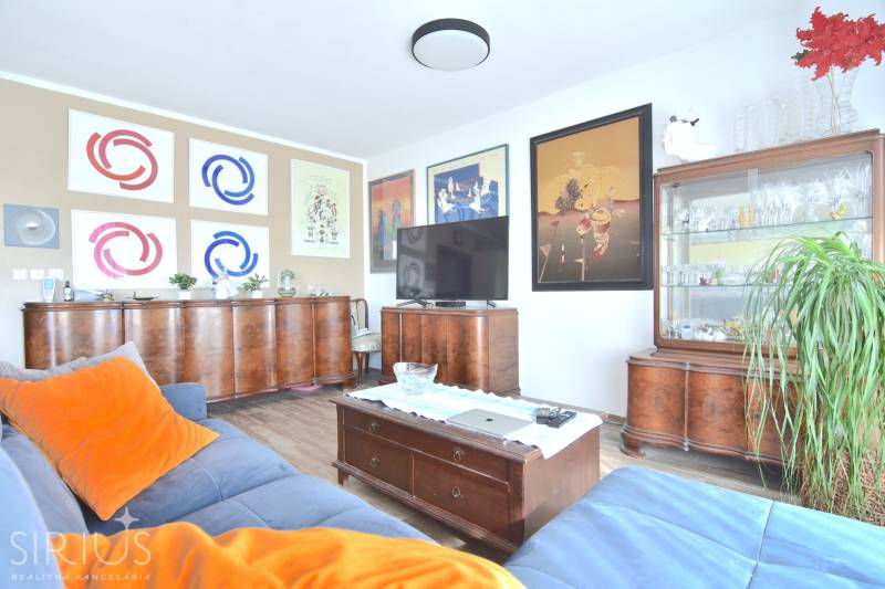 Living room in a 3-room apartment with wooden furniture, a floor with a wooden decor, and paintings on the walls.