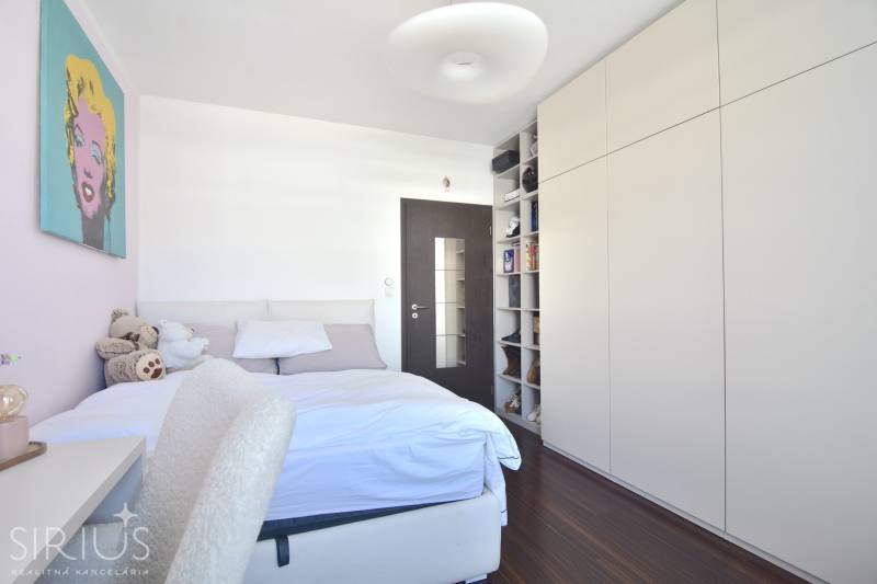 A bedroom with a built-in wardrobe, a wooden decor floor, and artwork. A 3-room apartment.