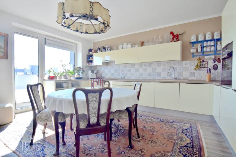 A kitchen in a 3-room apartment with a round table, carpets, and a decorative chandelier.