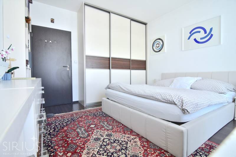 Bright bedroom with an upholstered bed, carpet, large built-in wardrobe, wall decorations.