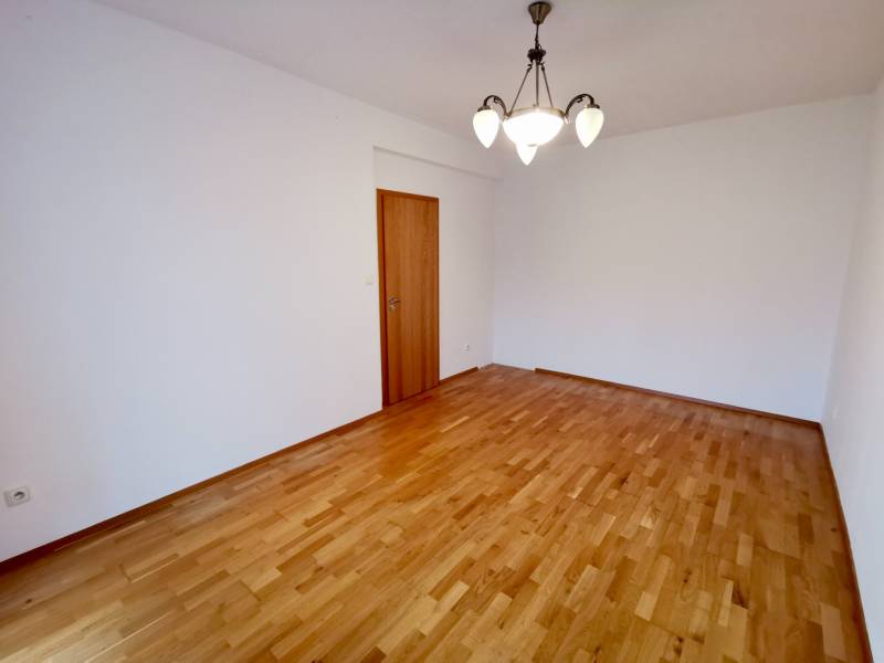 A room with a wooden decor floor and a light fixture in a 4-room apartment.