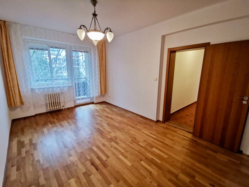 A room in a 4-room apartment with a wooden decor floor and curtains.