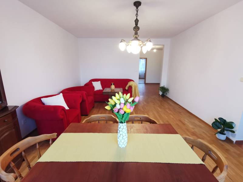 4-room apartment with red seating, dining table, and floor with wood decor.