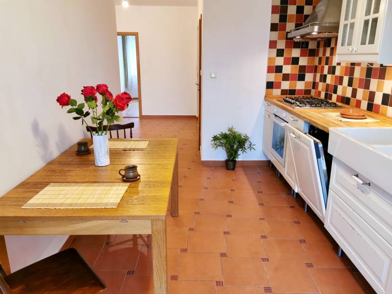 A kitchen area with tiles and a dining table with a vase in a 4-room apartment.