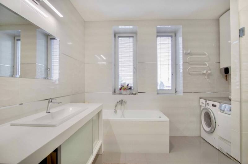 A bathroom in a 3-room apartment with a shower, a washing machine, and windows with blinds.