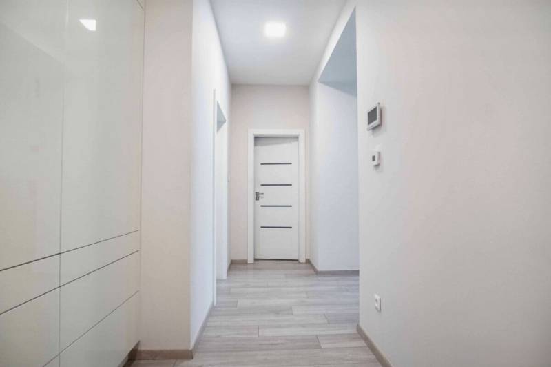 A hallway in a 3-room apartment with a wooden decor floor and white doors.