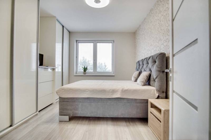 Stylish bedroom in a 3-room apartment with a large bed, wardrobe, and wooden floor decor.