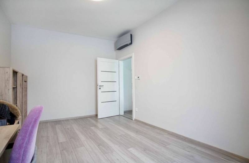 Interior with white walls, wood-patterned flooring, and simple furniture in a 3-room apartment.