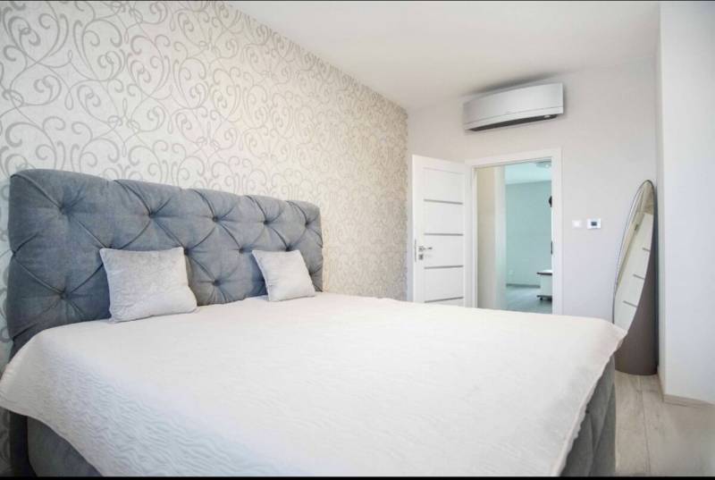 A bedroom with patterned wallpaper, a large bed, and air conditioning in a 3-room apartment.
