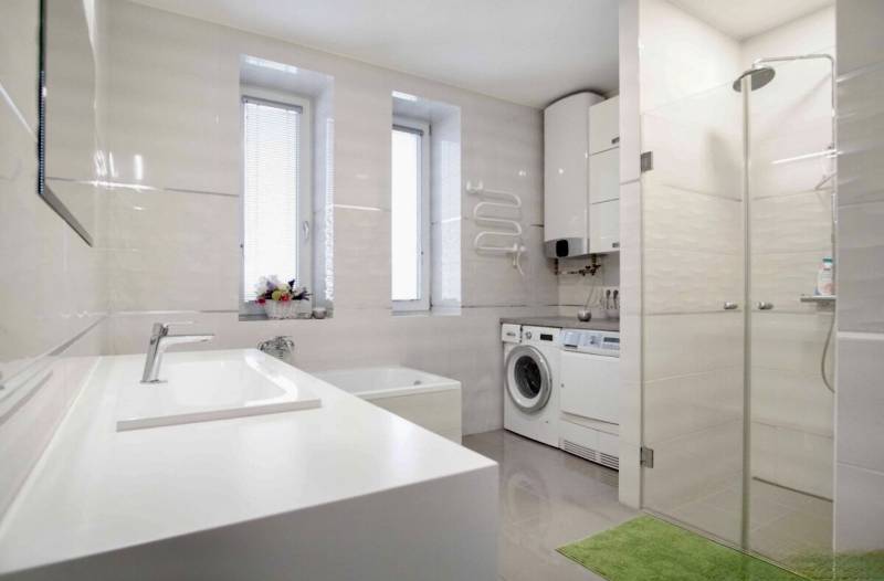 A bathroom in a 3-room apartment with a bathtub, shower, and washing machine.