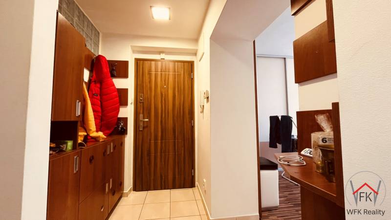 Entrance hallway in a 3-room apartment with tiles and wooden decor on the doors.