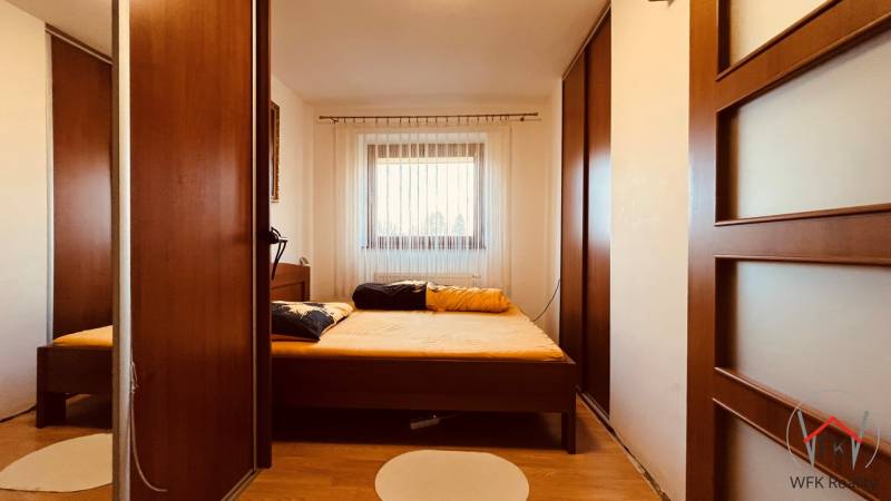 A bedroom in a 3-room apartment with a wooden decor floor and large wardrobes.