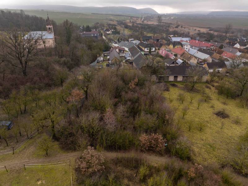 A view of greenery, houses, and a church in Gemerské Teplice on recreational grounds.