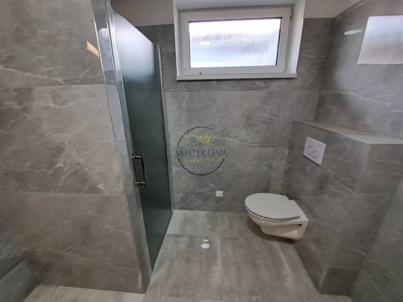 A bathroom in a family house with tiled walls and a shower enclosure.