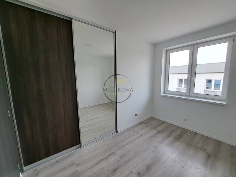 A room in a family house with a wooden decor floor and a large mirrored wardrobe.