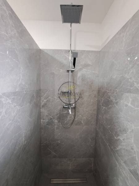 Gray tiles in the shower corner of a family house with a rain shower and a handheld shower.