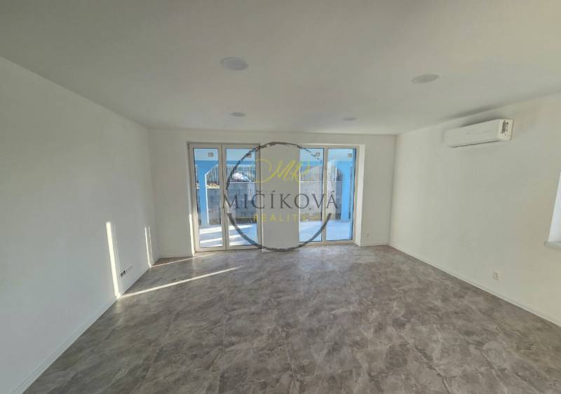 A spacious room with tiled flooring and glass doors in a family house.