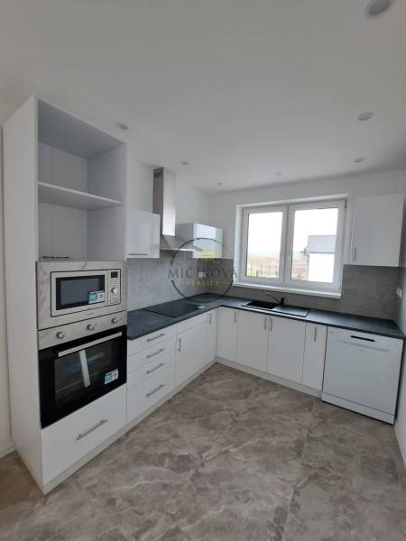 A kitchen in a family house with white cabinets and built-in appliances.