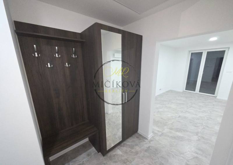 A hallway with a coat rack and a mirror in a family house with a wooden decor floor.