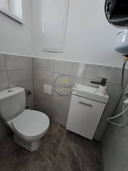 A bathroom in a family house with a toilet, a sink, and a floor with a wooden decor.