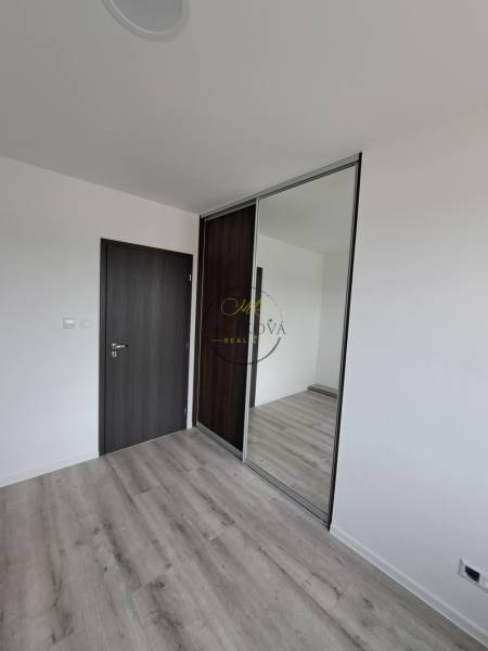 A room with a wooden decor floor, dark doors, and a built-in wardrobe in a family house.