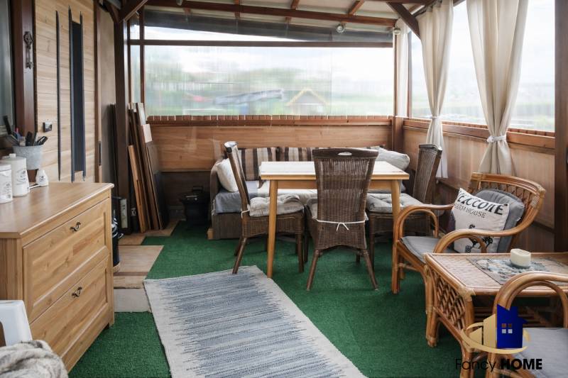 Gardens with rattan furniture, green carpet, and wooden decor.