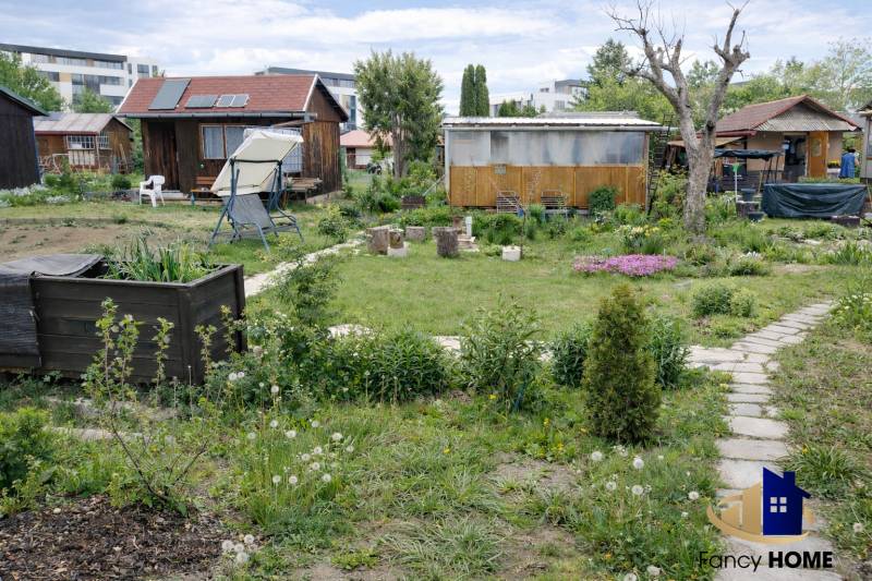 Gardens on Brežný Row in Poprad with cottages, greenery, and a relaxation corner.