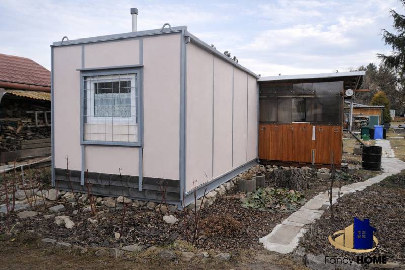 Gardens on Brežný Riadok in Poprad depict a wooden cottage with a surrounding garden.