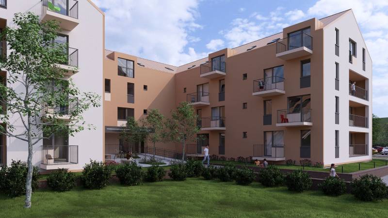 An apartment building in Poprad surrounded by greenery with balconies and passing people.