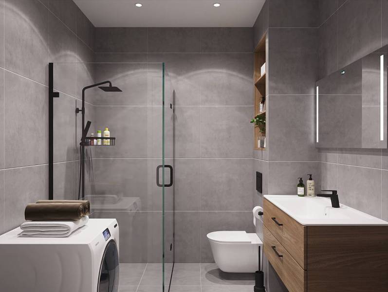 Bathroom in a studio apartment with a washing machine, shower, and wooden decor furniture.
