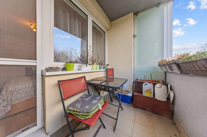 A balcony of a 4-room apartment with flower pots and chairs, ideal for relaxation.