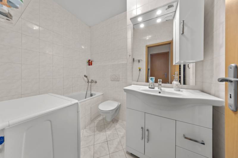 White bathroom with a bathtub and sink in a 4-room apartment.